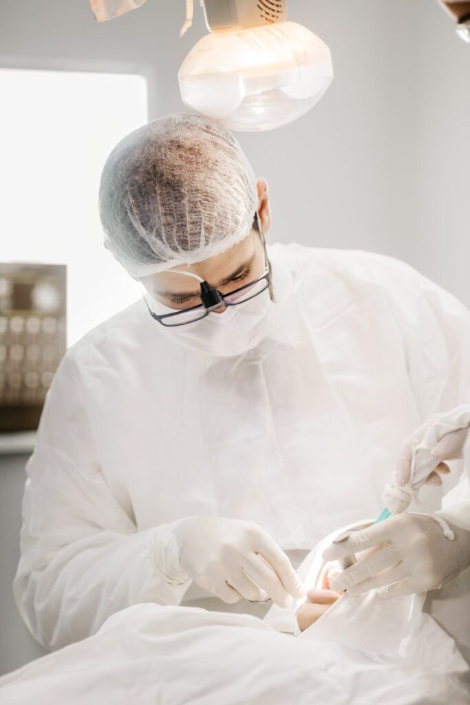 Dentist in protective gear performing a procedure in a sterile dental clinic setting.