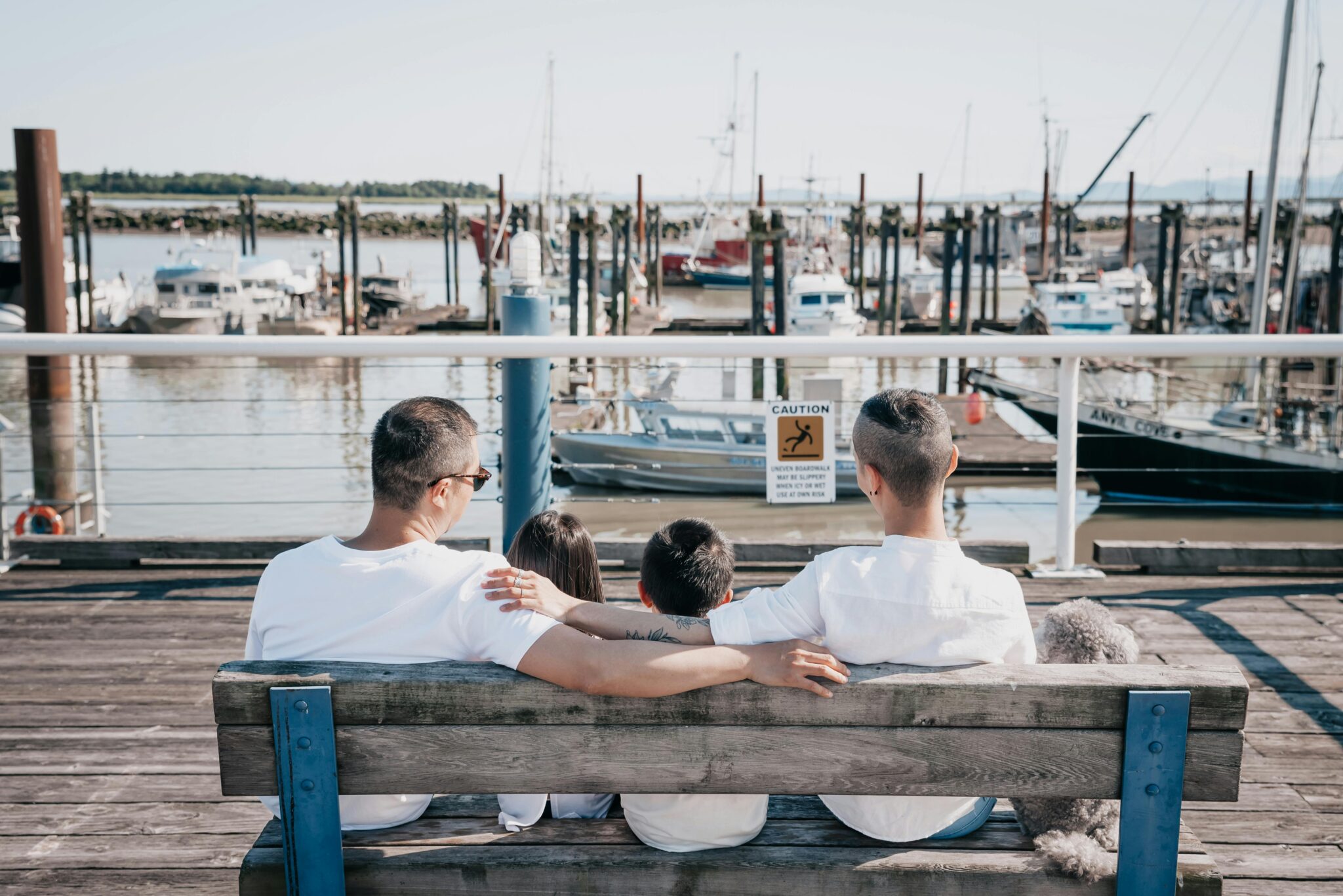 A family enjoys a tranquil moment together on a marina bench, embracing nature and connection.